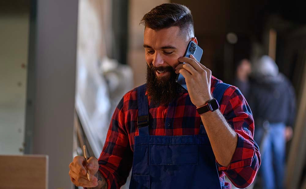 Black sedan parked by a glass building with trees and hills in the background.